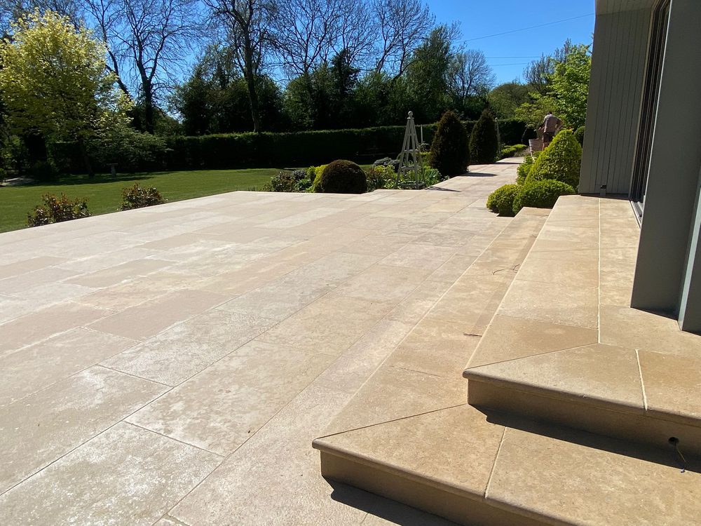 A honed limestone patio with bullnose steps in a Suffolk country garden by Eastscape
